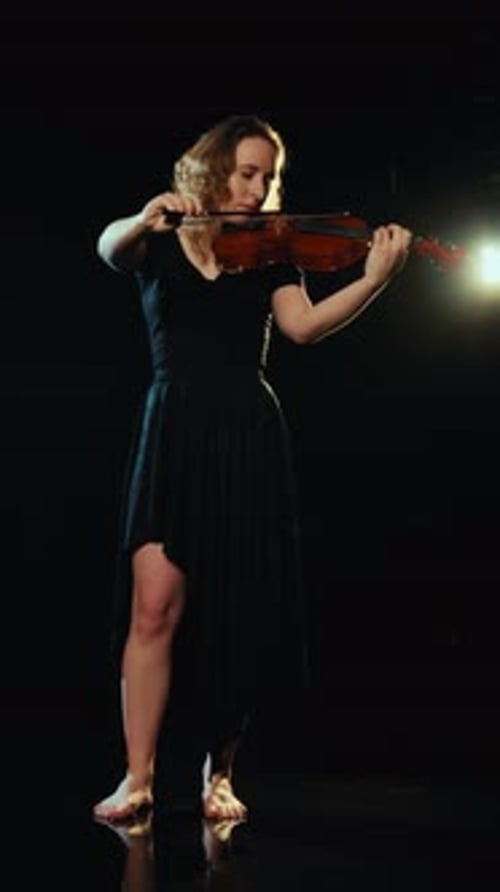 Woman Plays Violin in Dark Studio Performance