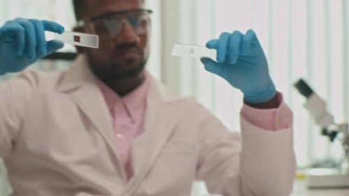 Scientist Inspecting Microscope Slides in a Lab