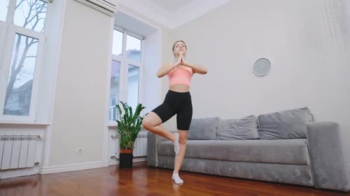 Woman Balances in Yoga Tree Pose at Home