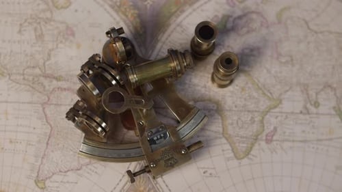 A brass sextent navigation instrument on a vintagemap of the world