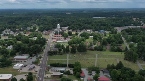 High altitude drone flyover of a small town area towards a silver water tower.