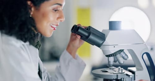 Woman Using Microscope in Brightly Lit Laboratory