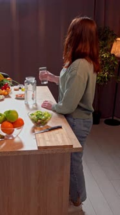 Woman Drinks Water While Preparing Healthy Meal