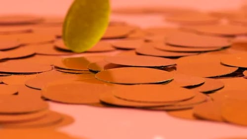 Falling confetti on a peach-pink background. Slow motion.