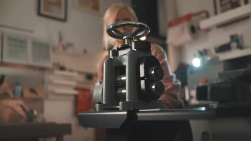 Female Jeweler Using a Rolling Mill Machine in Her Workshop