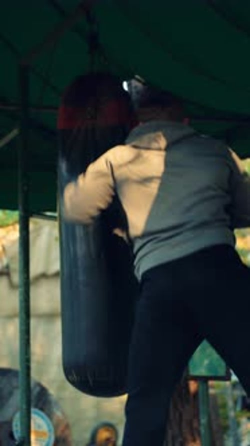 Man Boxing with a Punching Bag in an Outdoor Gym