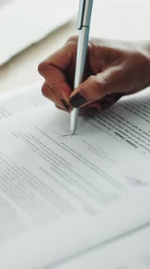 Woman's Hand Signing Official Document with Pen