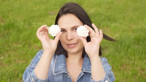 Smiling Woman Holds Marshmallows Up to Eyes