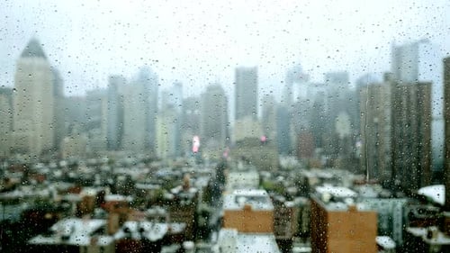 Raindrops on Glass with Blurred Cityscape Background