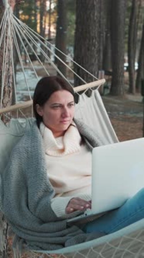 Woman Working Remotely on Laptop in Hammock in Winter Forest