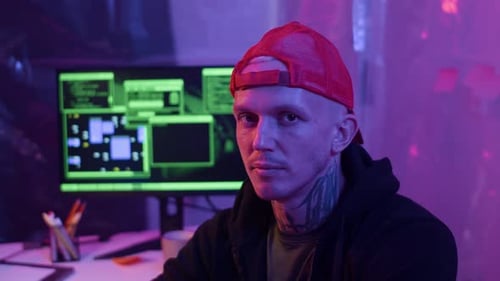 Young Man Coding in Purple Illuminated Room