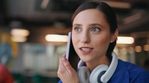 Happy Hipster Calling Cellphone Sitting Urban Cafe with Headset on Neck Closeup
