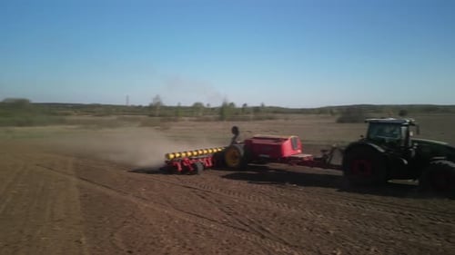 Green tractor works on the field planting sugar beet in spring in Ukraine