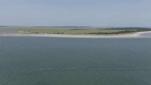 An inlet opens to wide, protected marshland across the water, with grassy textures and undisturbed s