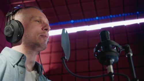 Homme chantant en studio d'enregistrement avec fond de panneau acoustique