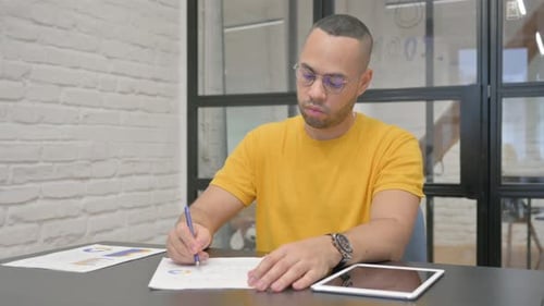 Hispanic Man Working on Documents in Office