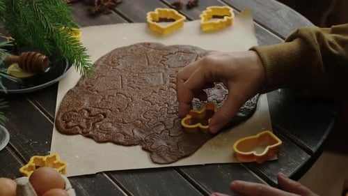 Hands Cutting Christmas Cookie Shapes From Dough