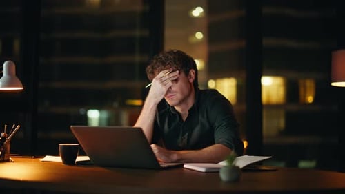 Tired Man Working at Desk at Night