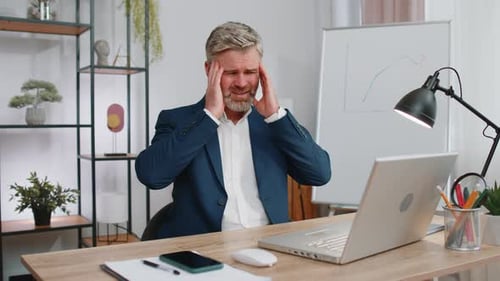 Man in Suit Experiencing Stress at Desk