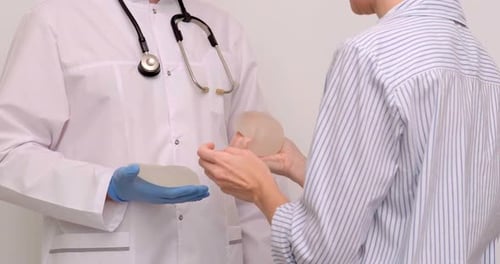 Doctor and Patient Exam Consultation in Clinic Office Holding Breast Enlargement Implant in Hands