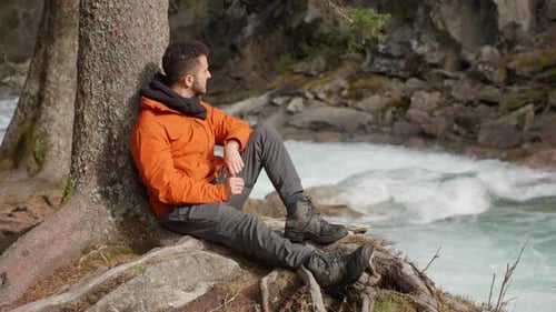 Junger Mann entspannt sich an einem Fluss im Wald an einem ruhigen Nachmittag in der Natur