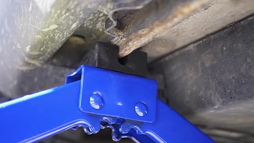 Hydraulic car jack adjustable scissor lift under vehicle for maintenance inspection close up