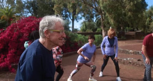 Active seniors enjoying stretching exercises together at Berlin city park on a sunny day