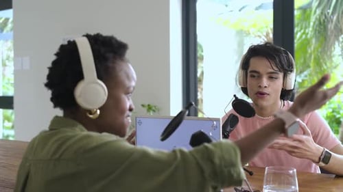 Divers collègues enregistrent un podcast en studio avec un homme faisant des gestes dans le micro puis une femme intercalant