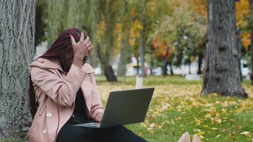 Excited Young Woman Freelancer Sitting in Autumn Park Working on Laptop Outdoors Reading Bad News