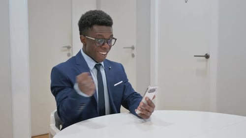 Young Man Celebrates Success Using Smartphone