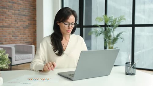 Dedicated MiddleAged Businesswoman Analyzing Documents in Office Setting