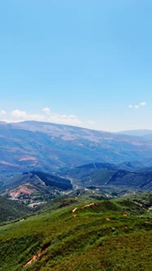 Green rocky landscape on sunny day. Drone footage descends above the mountain. Vertical video.