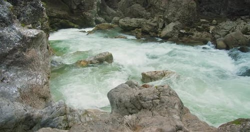 Clear stream running through boulders in rocky gorge. Abundant river flowing in slow-motion. Wild mo