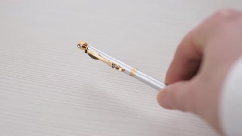 A Man's Hand Places a Pen on a White Table