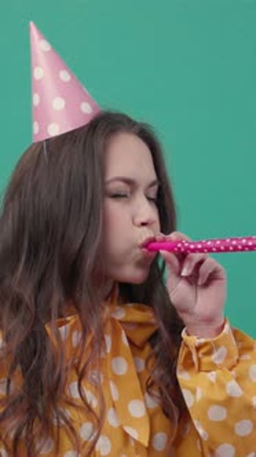 Woman Wearing Birthday Hat Blows Party Favor