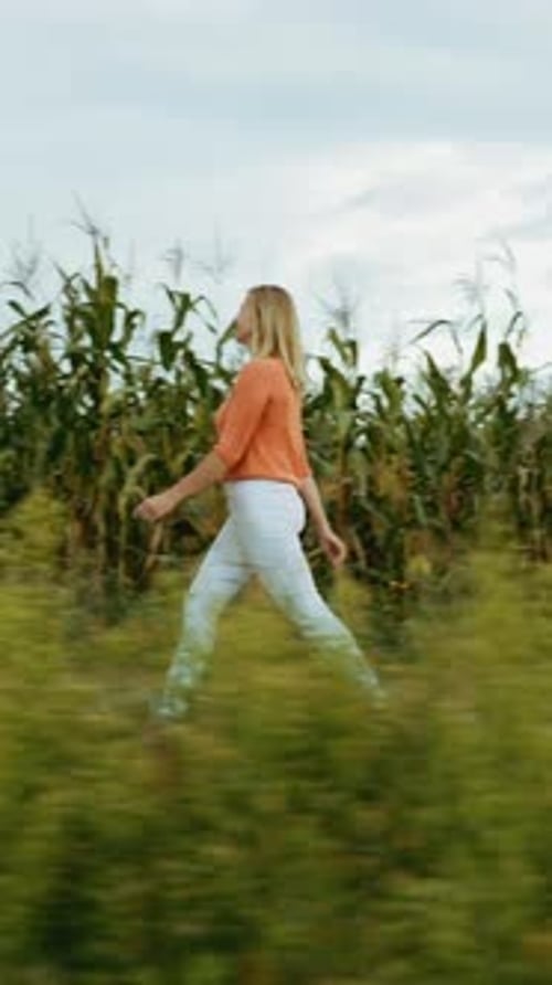 Woman Walking in Rural Field on Cloudy Day