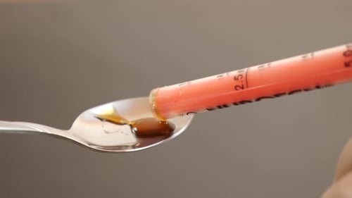 50 m. À l'aide d'un distributeur, le médicament est versé dans une cuillère.