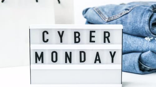 Zoom in Out Light Board with Text CYBER MONDAY with Paper Shopping Bags Jeans Clothes