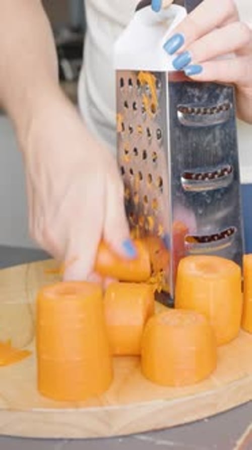 Woman grates peeled carrots in the kitchen