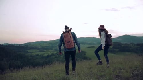 Couple with Backpacks Hiking Through a Grassy Mountain