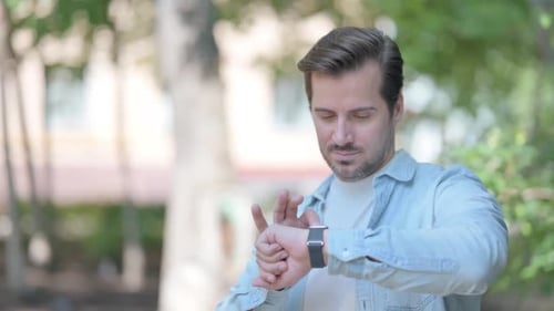 Man Using Smart Watch Device in Urban Park