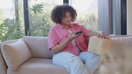 Woman Opening Package at Home on Sofa