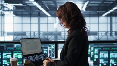 Woman in Data Center Using Laptop to Update Storage Arrays Holding Coffee Cup