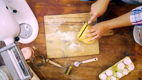 Woman Cutting Fresh Pasta Dough on Wooden Board