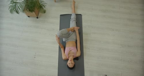 Athletic Young Woman Practicing Yoga Lying on Mat at Home View From Above