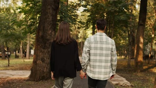 Unrecognizable Man and Woman Girlfriend and Boyfriend Holding Hands While Walking Down the Path in