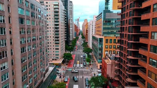 Flying above the multi-lane road along the building facades. Busy traffic on the street of New York