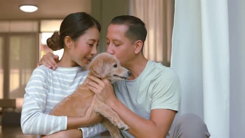 Young Couple Cuddling Adorable Dog Indoors