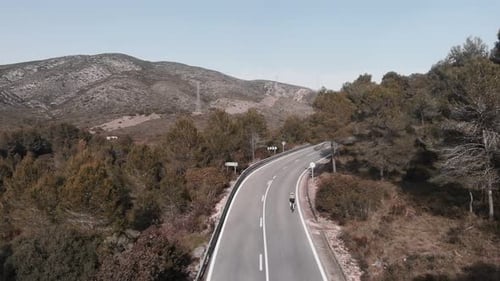 Motivated professional cyclist riding bicycle uphill in mountains against nature landscape