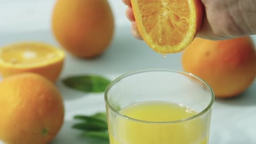 Squeezing orange into juice glass for breakfast